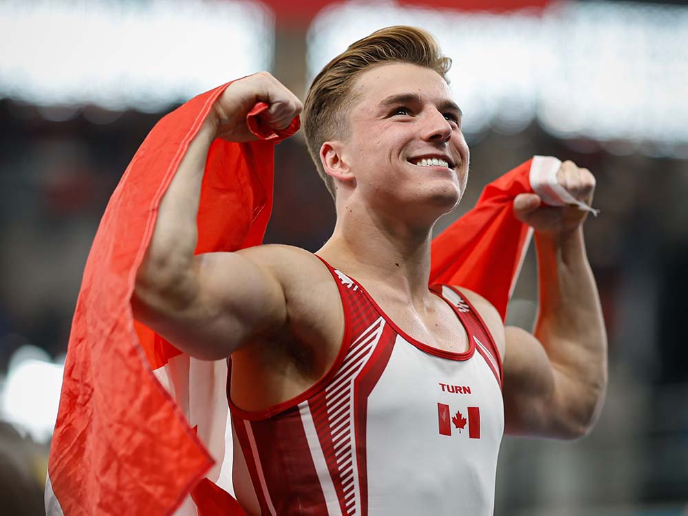 Félix Dolci smiles while holding a Canadian flag