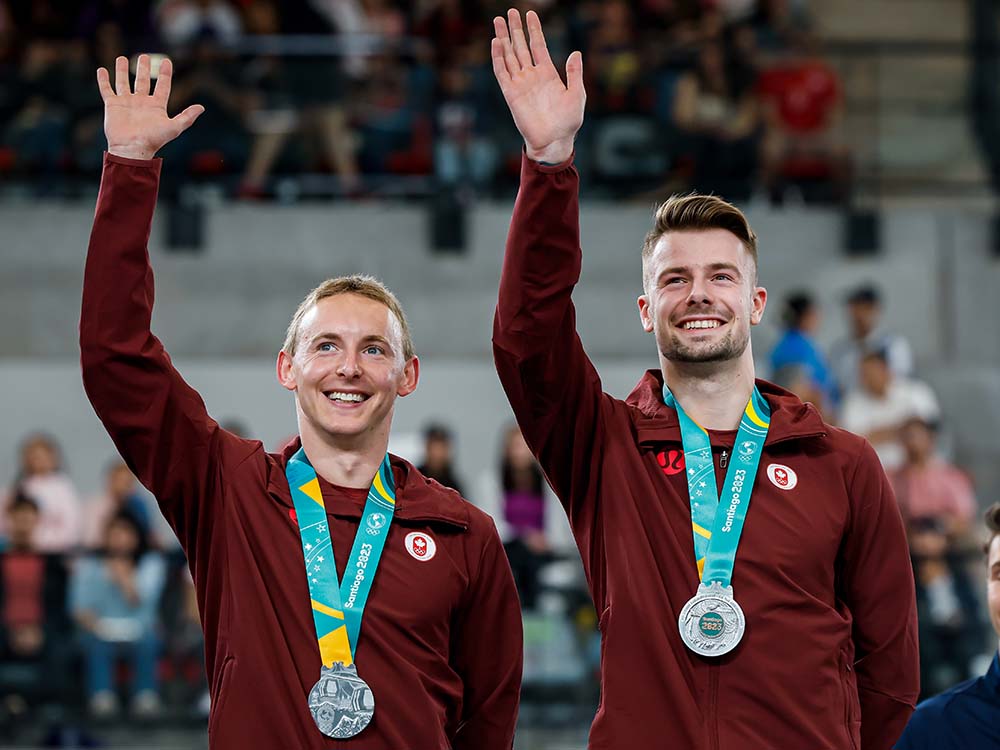 Two male gymnasts display medals earned in Synchro Trampoline