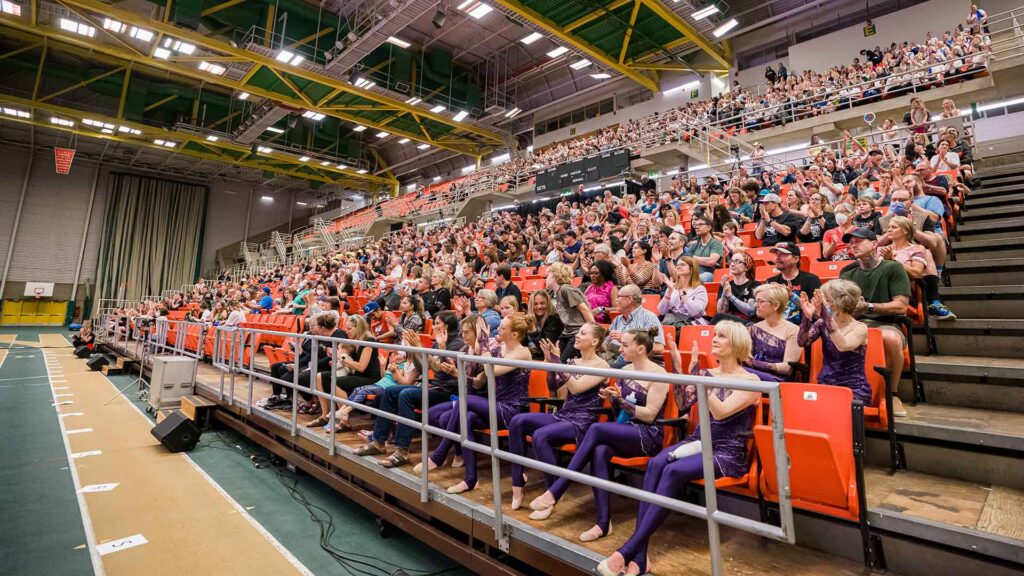 Gymnaestrada participants and spectators cheering in bleachers