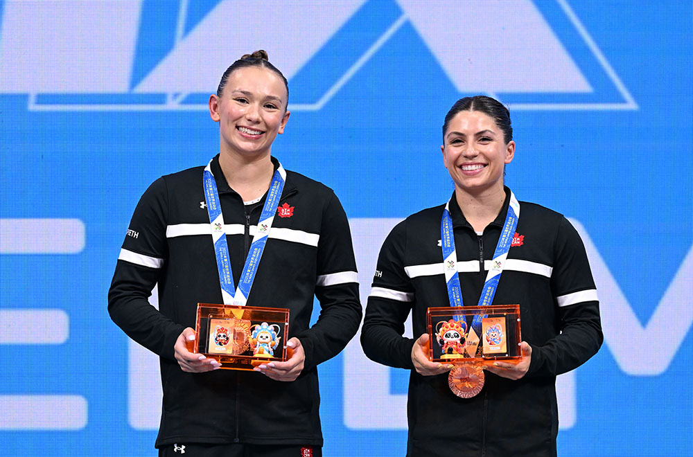 Two female athletes smiling with medals